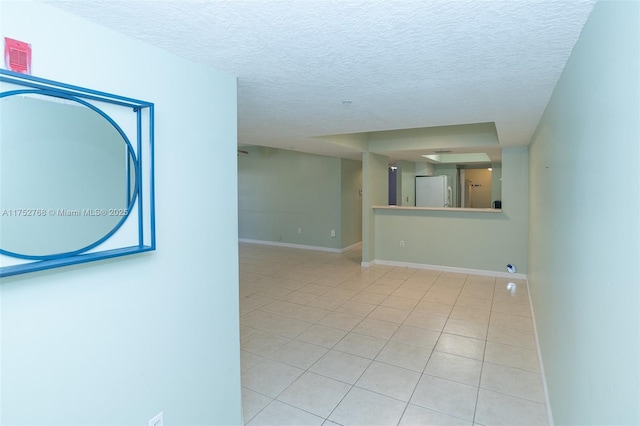 tiled empty room featuring a textured ceiling and baseboards