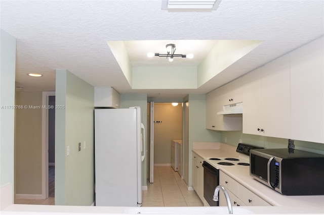 kitchen with washer / dryer, range with electric cooktop, stainless steel microwave, freestanding refrigerator, and under cabinet range hood