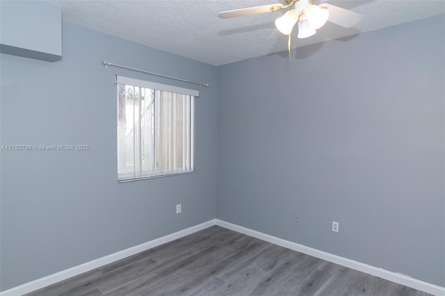 empty room with ceiling fan, a textured ceiling, baseboards, and wood finished floors