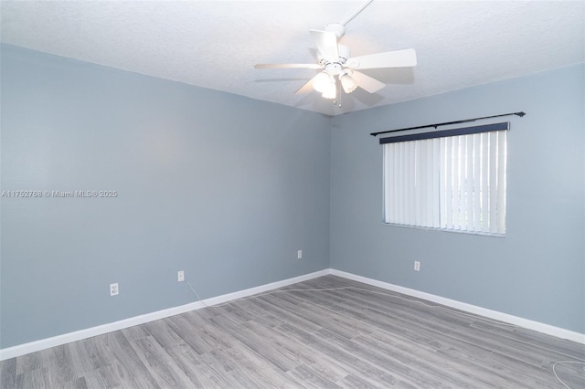 empty room featuring a textured ceiling, wood finished floors, a ceiling fan, and baseboards