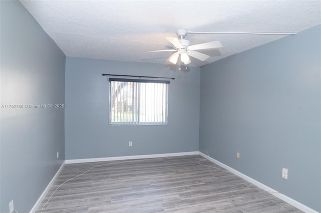 spare room with ceiling fan, a textured ceiling, baseboards, and wood finished floors