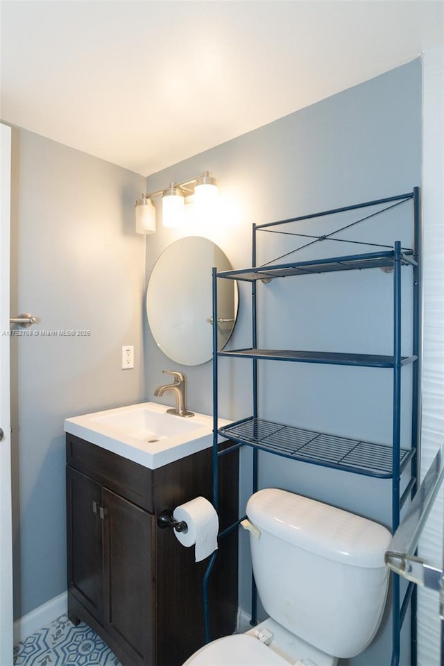 half bath with vanity, toilet, and baseboards