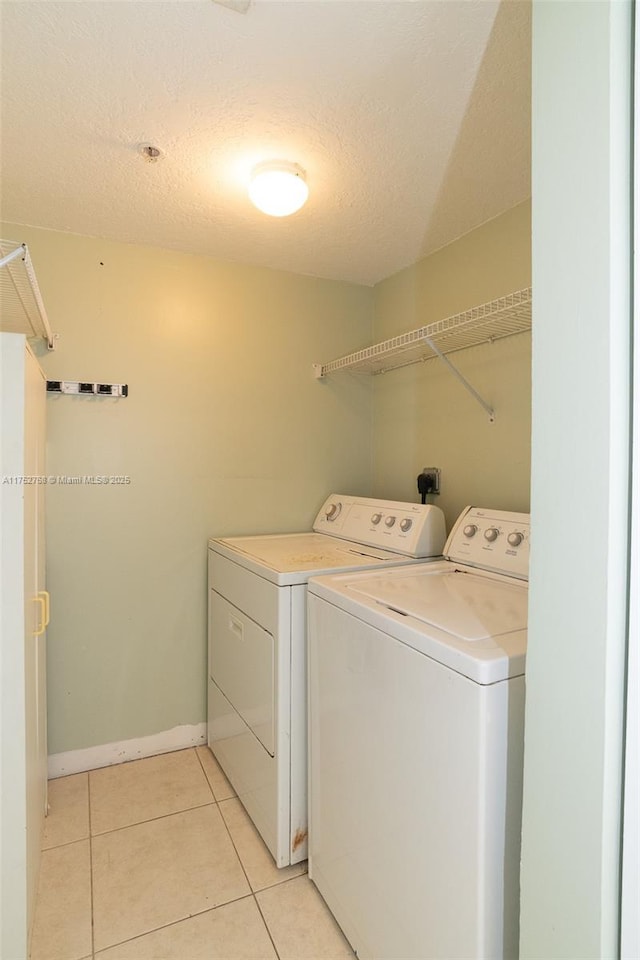 clothes washing area with light tile patterned floors, laundry area, a textured ceiling, and washer and dryer