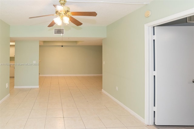 empty room with light tile patterned floors, baseboards, visible vents, and a ceiling fan