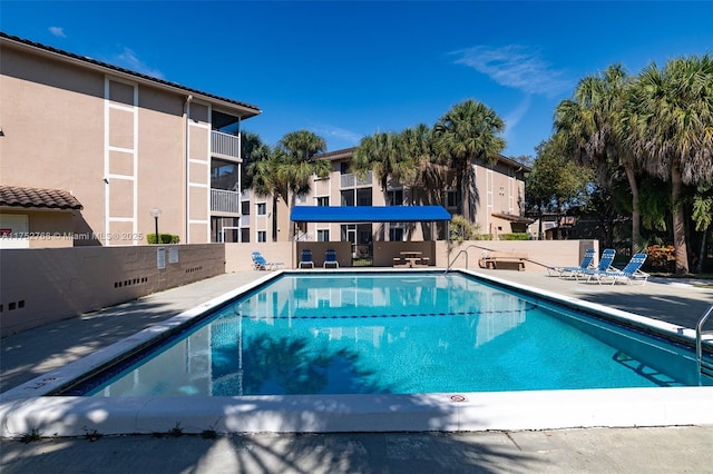 community pool with a patio area and fence