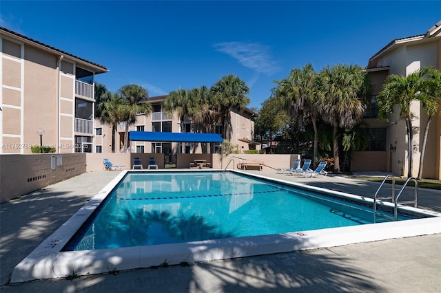 community pool with a patio and fence