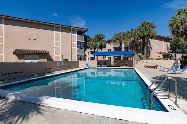 community pool with a patio area and fence