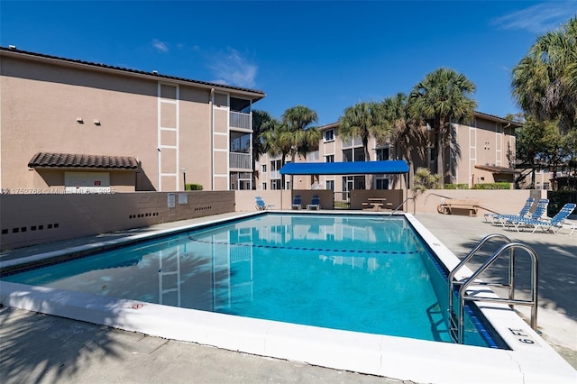 community pool with a patio area and fence