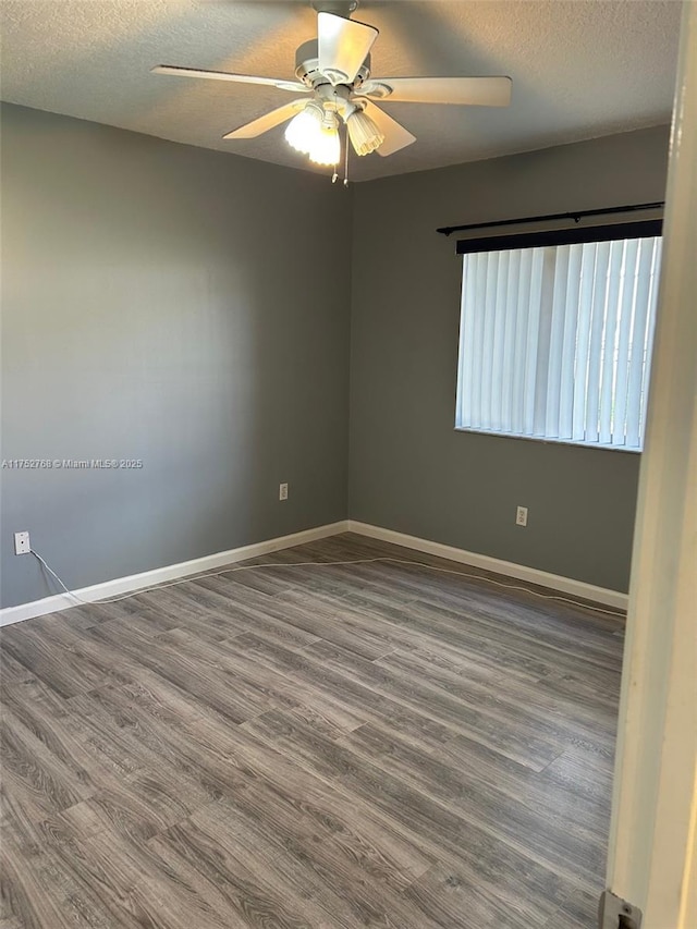 spare room featuring a textured ceiling, baseboards, and wood finished floors