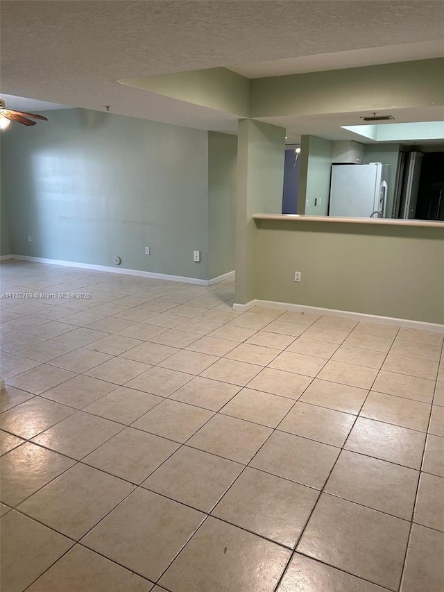 unfurnished room featuring light tile patterned floors, a textured ceiling, and baseboards