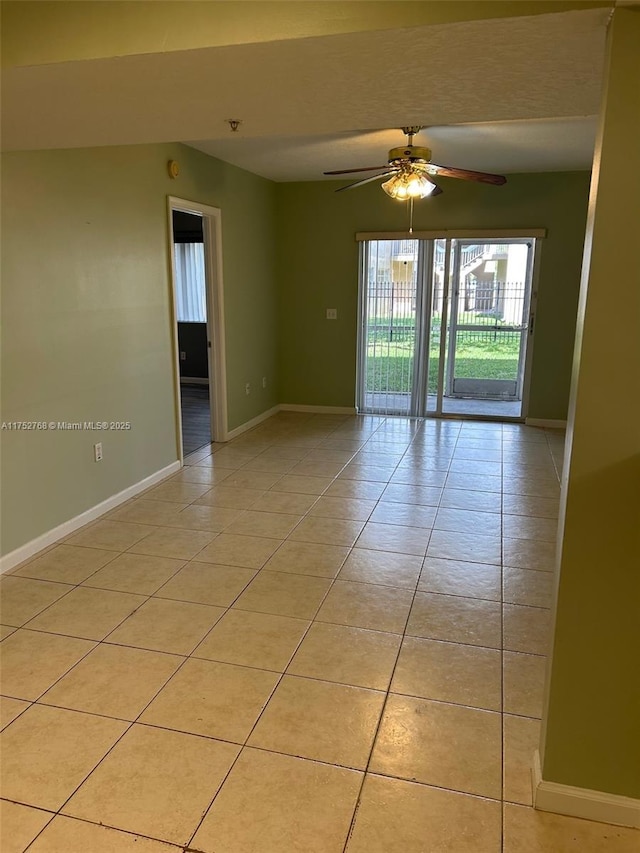 empty room with light tile patterned floors, ceiling fan, and baseboards