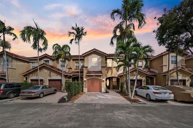 multi unit property with decorative driveway, a tiled roof, and stucco siding