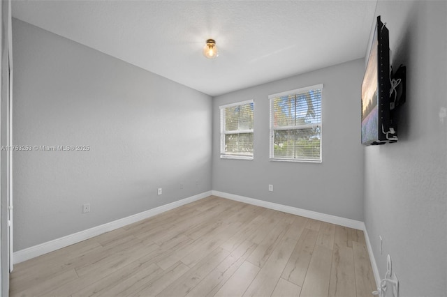 empty room featuring light wood finished floors and baseboards