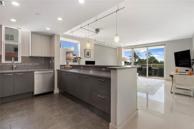 kitchen featuring tasteful backsplash, a peninsula, a sink, gray cabinetry, and stainless steel dishwasher