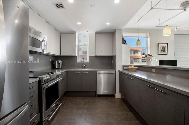 kitchen featuring recessed lighting, stainless steel appliances, a sink, visible vents, and decorative backsplash