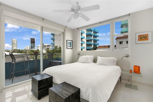 bedroom featuring a ceiling fan, access to exterior, a city view, and baseboards