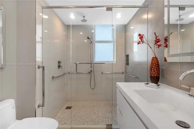 full bath featuring a stall shower, tile walls, toilet, and vanity