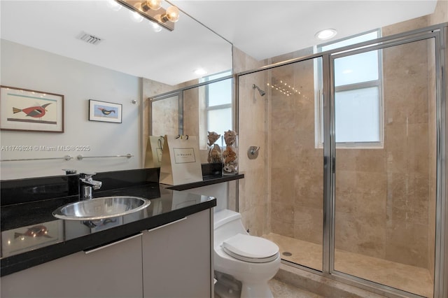 full bathroom with toilet, vanity, a shower stall, and visible vents