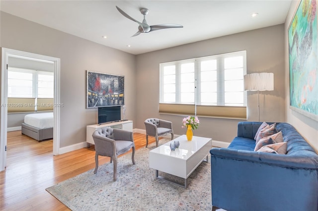 living room featuring a healthy amount of sunlight, ceiling fan, baseboards, and wood finished floors