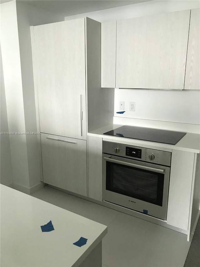 kitchen featuring modern cabinets, stainless steel oven, black electric stovetop, and light countertops