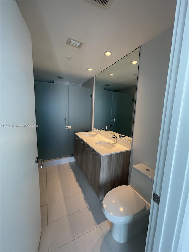 bathroom with tile patterned floors, toilet, a sink, recessed lighting, and double vanity