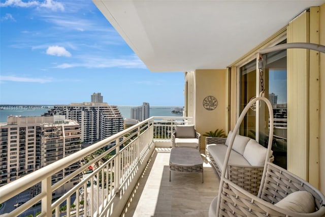 balcony with an outdoor living space, a water view, and a city view