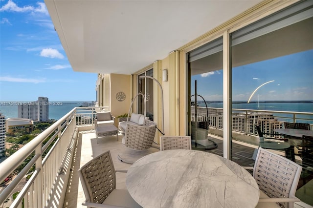 balcony featuring outdoor dining area and a water view