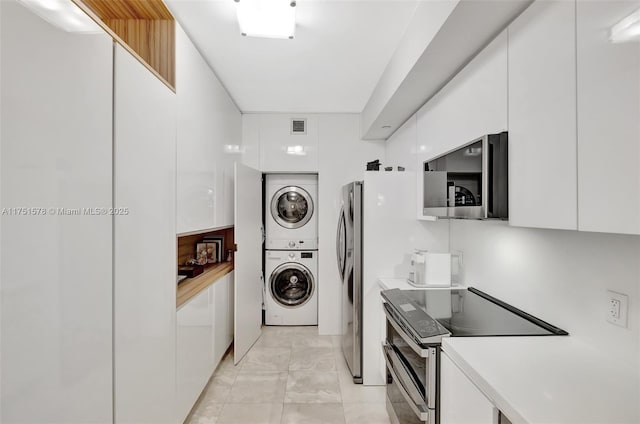 laundry room featuring stacked washer and dryer, laundry area, and visible vents