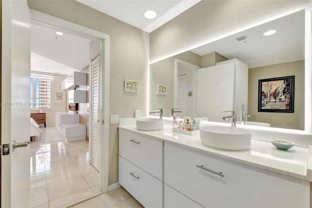 ensuite bathroom featuring ensuite bathroom, double vanity, a sink, and visible vents