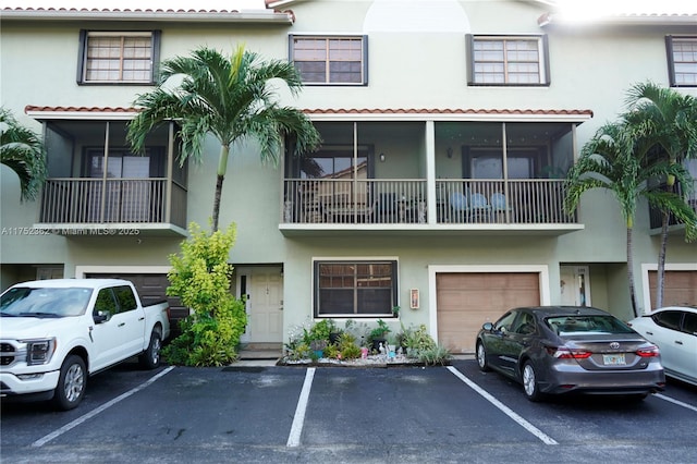 view of front of house with uncovered parking, an attached garage, and stucco siding