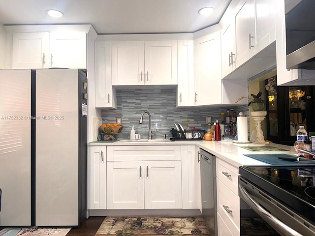 kitchen with stainless steel appliances, a sink, white cabinetry, light countertops, and tasteful backsplash