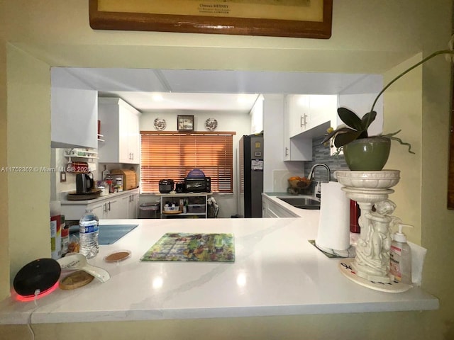 kitchen featuring white cabinetry, light countertops, a sink, and freestanding refrigerator