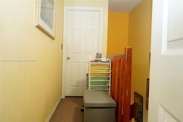 hall featuring carpet flooring and baseboards