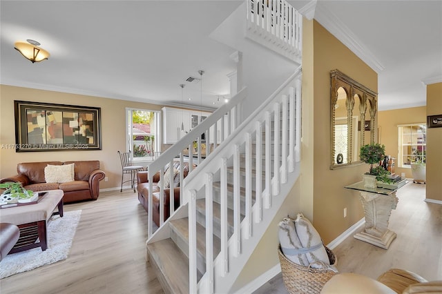 stairway with ornamental molding, wood finished floors, visible vents, and baseboards