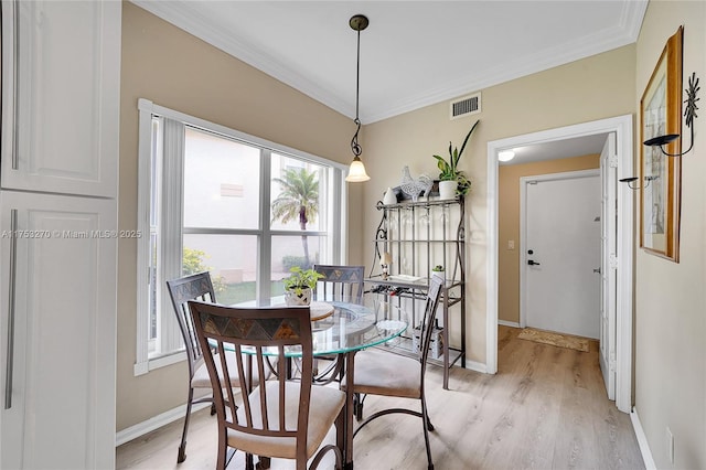 dining area with light wood-style floors, visible vents, crown molding, and baseboards