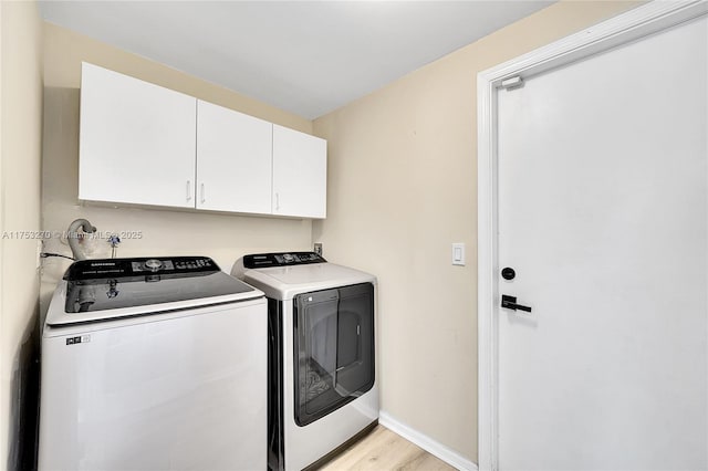 laundry area featuring baseboards, washing machine and dryer, cabinet space, and light wood-style floors