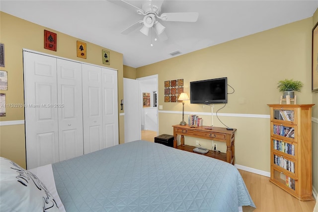 bedroom featuring visible vents, baseboards, a ceiling fan, light wood-style floors, and a closet