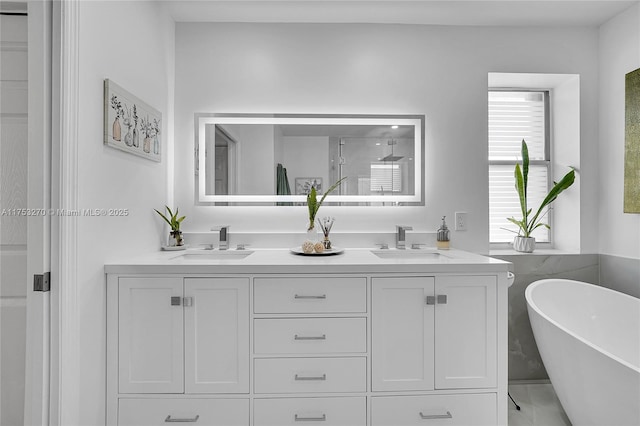 full bath featuring double vanity, a freestanding bath, walk in shower, and a sink