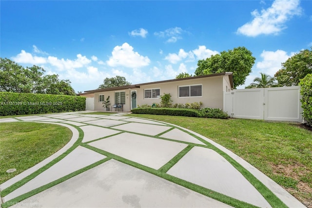 ranch-style house featuring a front yard, a gate, fence, and stucco siding