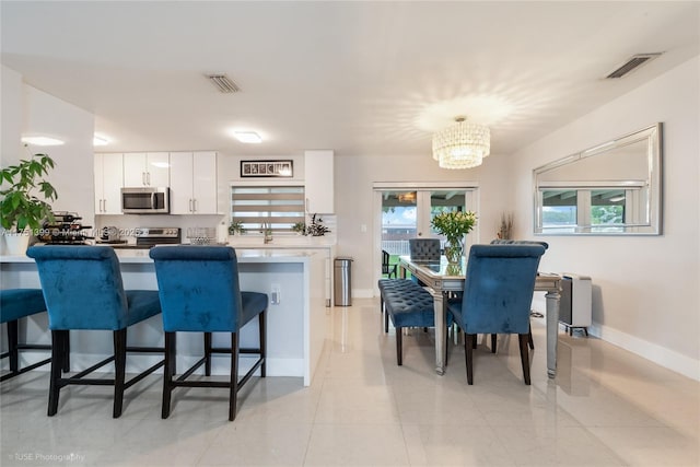 kitchen featuring a kitchen breakfast bar, stainless steel appliances, visible vents, and white cabinets