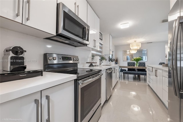 kitchen featuring an inviting chandelier, white cabinetry, appliances with stainless steel finishes, and light countertops