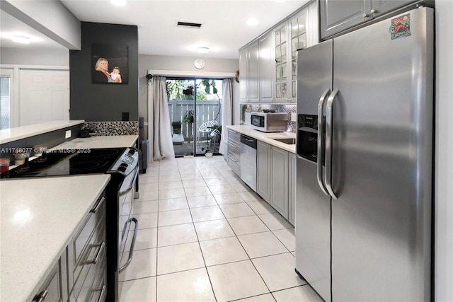 kitchen with light tile patterned flooring, visible vents, appliances with stainless steel finishes, gray cabinets, and glass insert cabinets