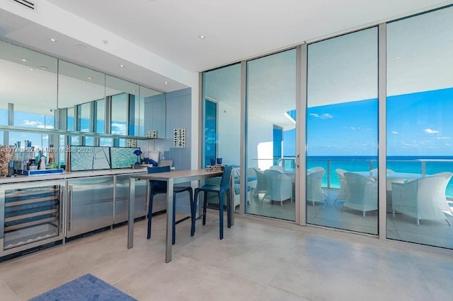 bar featuring beverage cooler, visible vents, floor to ceiling windows, and concrete flooring