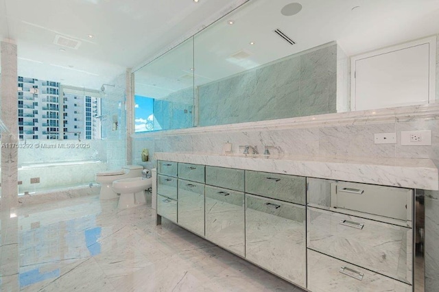 full bathroom featuring a tub with marble appearance, toilet, marble finish floor, vanity, and a bidet