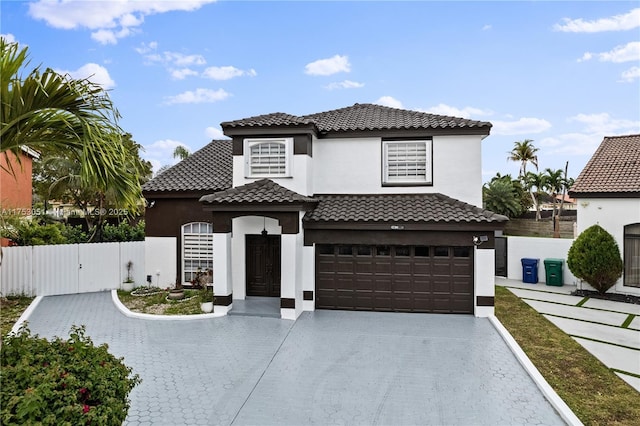 mediterranean / spanish-style home with a gate, fence, concrete driveway, and stucco siding