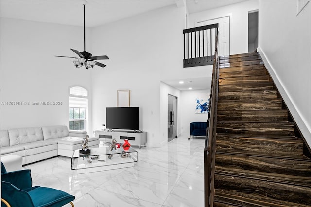 living room with stairs, marble finish floor, ceiling fan, and baseboards