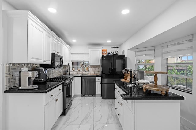 kitchen featuring dark countertops, black appliances, white cabinets, and backsplash