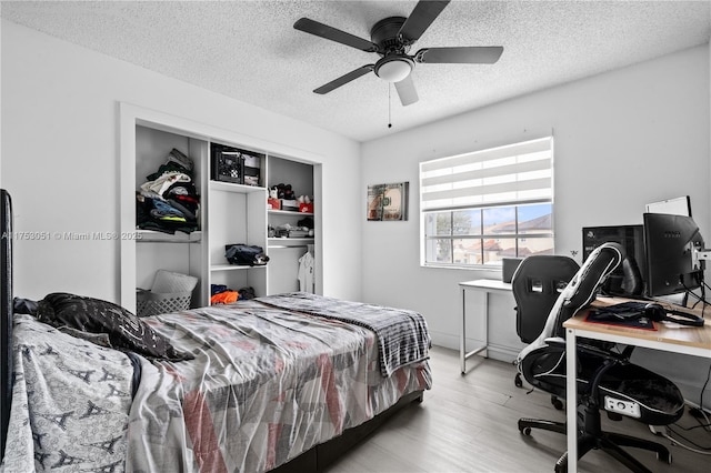 bedroom with a closet, ceiling fan, a textured ceiling, and light wood finished floors