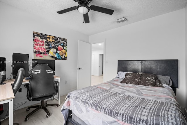 bedroom with visible vents, ceiling fan, a textured ceiling, and wood finished floors