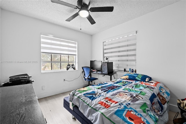 bedroom featuring a textured ceiling, wood finished floors, a ceiling fan, and baseboards